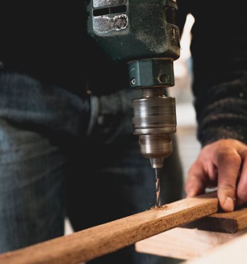 Woodworking - Man Holding Wooden Stick While Drilling Hole