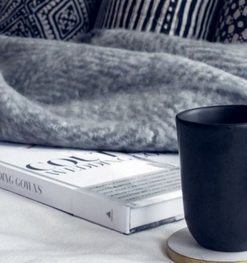 Blanket - Black Ceramic Mug on Round White and Beige Coaster on White Textile Beside Book