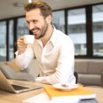 Work - Depth of Field Photo of Man Sitting on Chair While Holding Cup in Front of Table