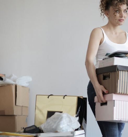 Clutter - Concentrated woman carrying stack of cardboard boxes for relocation