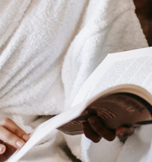 Routine - Young black female in bathrobe and towel sitting on chair with book and enjoying daily routine while relaxing in cozy room