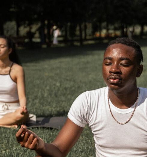 Mindfulness - Full body of flexible barefoot couple in activewear sitting on mats in Lotus pose with closed eyes while practicing yoga together