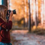 Lifestyle - Woman Leaning Back on Tree Trunk Using Black Dslr Camera during Day