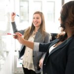 Workplace - Two Women in Front of Dry-erase Board