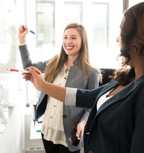 Workplace - Two Women in Front of Dry-erase Board