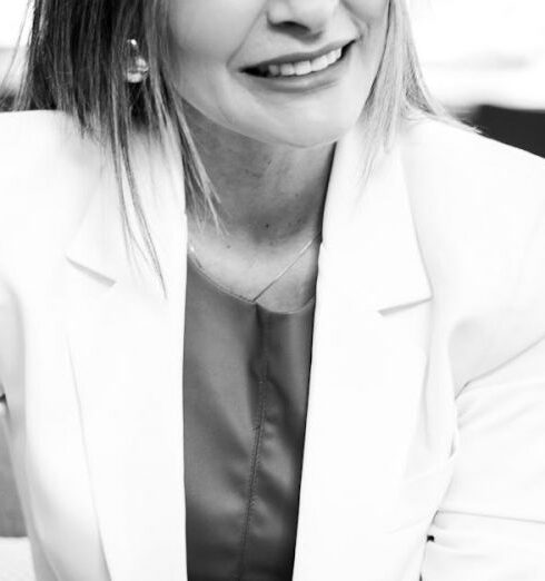 Role - Smiling Woman in Blazer and Trousers Sitting in an Armchair