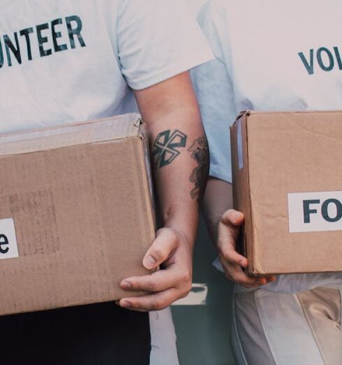 Volunteering - Man and Woman Carrying Medicine and Food Labelled Cardboard Boxes Behind a White Van