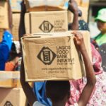 Food Bank - People Walking and Carrying Boxed on Their Heads