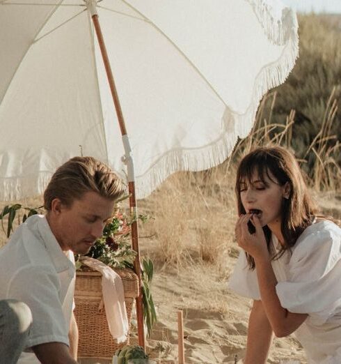 Commitments - Young couple having picnic on sandy terrain