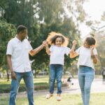 Family - A Man and a Woman Assisting a Girl While Jumping