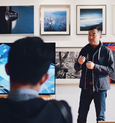 Mentoring - Man Beside Flat Screen Television With Photos Background