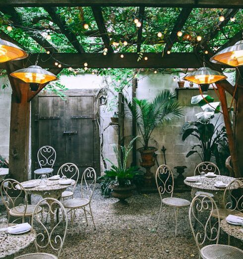 Pergola - Cafe with setting on ornamental tables near chairs under decorative lamps in backyard on summer day