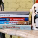 Guidebook - Stack of Books Beside a Ceramic Decoration on Marble Top Table