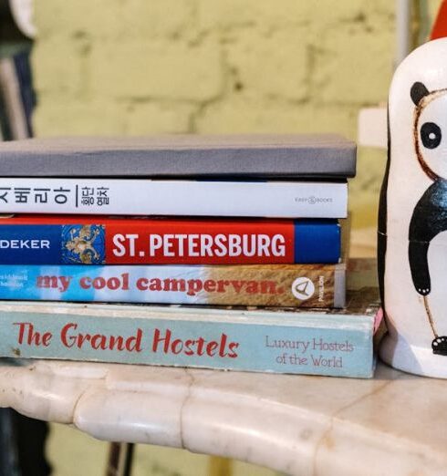 Guidebook - Stack of Books Beside a Ceramic Decoration on Marble Top Table