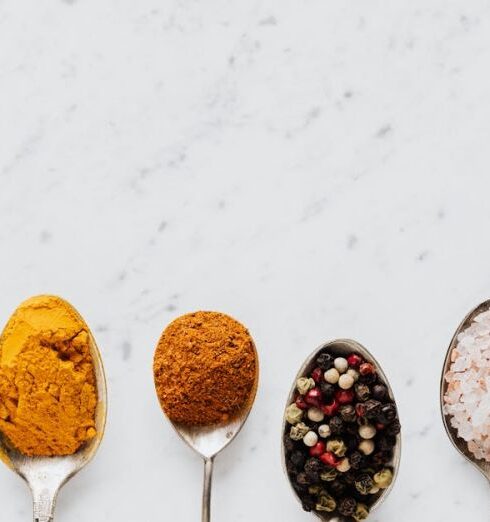 Cooking - Top view of assorted aromatic condiments arranged together in metal spoons on marble surface used for delicious gourmet meal cooking