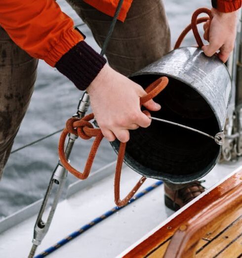 Fishing - Man in Orange Jacket and Gray Pants Holding Black and Red Fishing Rod