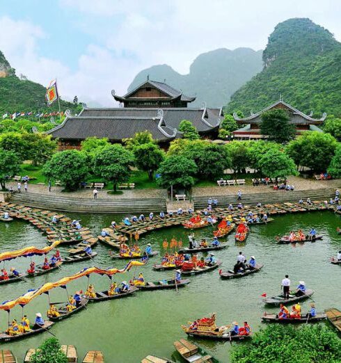 Boat Festival - Aerial Photography of Building Surrounded With Body of Water With Boats Across Tree Covered Hills