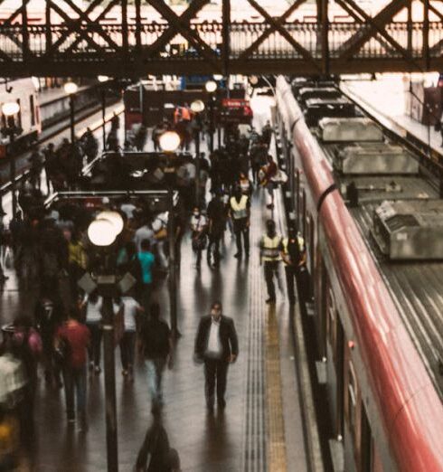 Train Journeys - From above of crowd of people on asphalt platform with trains under large semi circular metallic ceiling at railway station