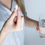 Drink Water - Woman Holding Half-full Glass and White Medicine Pill