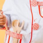 Chef Experience - Adorable African American child wearing uniform of cook standing with kitchen tools in studio