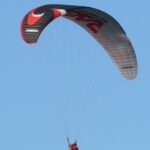 Adventure Experiences - Paraglider flying in the blue sky on a sunny day - Paraglider soaring like a boss in the sunny blue yonder.