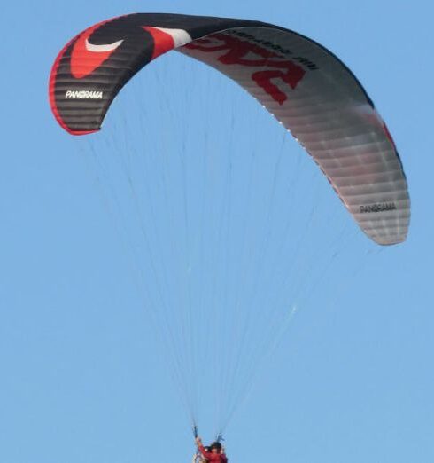 Adventure Experiences - Paraglider flying in the blue sky on a sunny day - Paraglider soaring like a boss in the sunny blue yonder.