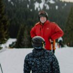 Ski Trip - Group of men with snowboard and ski on snowy terrain near trees under cloudy sky on weekend