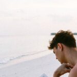 Books - Topless Man Reading Book While Seating at Beach