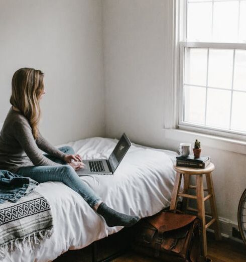 Travel Blogs - Woman in Gray Shirt Sitting on Bed