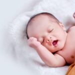 Baby - Baby Lying On White Fur With Brown Blanket