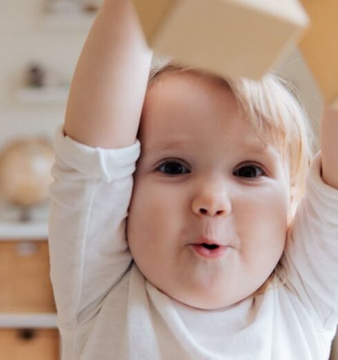 Toddlers - Baby in White Onesie Holding Wooden Blocks