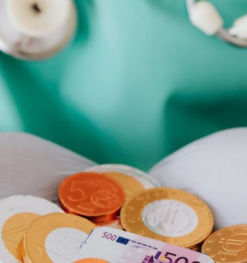 Insurance - From above crop faceless doctor with stethoscope on shoulders holding in hands chocolate coins