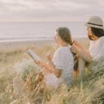 Beach Reads - Man and Woman Sitting on Grass Field