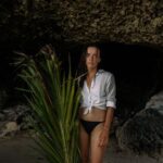 Hidden Beaches - Sad woman in bikini standing with palm branch in cave