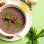 Meal Prep - A bowl of soup with mushrooms and bread on a green background