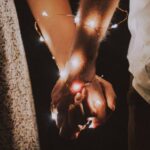 Couples - Man and Woman Holding Each Others Hand Wrapped With String Lights