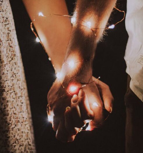 Couples - Man and Woman Holding Each Others Hand Wrapped With String Lights