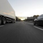 Routes - Blue Infiniti Sedan Running on Road Togerther With White Freight Truck