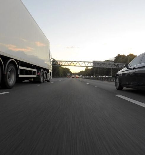 Routes - Blue Infiniti Sedan Running on Road Togerther With White Freight Truck