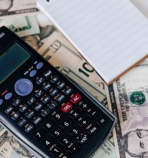 Insurance - From above electronic calculator and notepad placed over United States dollar bills together with metallic pen for budget planning and calculation