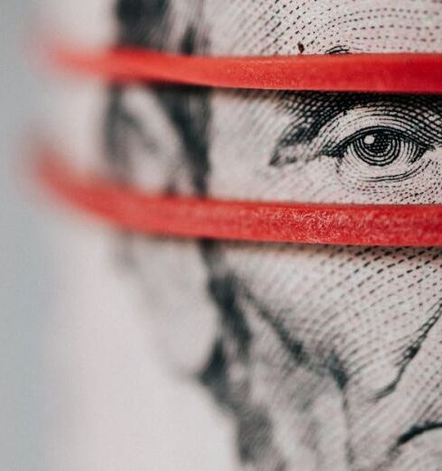 Budget - Closeup of rolled United States five dollar bills tightened with red rubber band