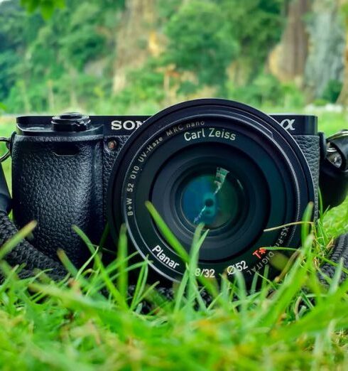 Photography - Black Sony Dslr Camera on Green Grass in Front of Brown and Green Mountain