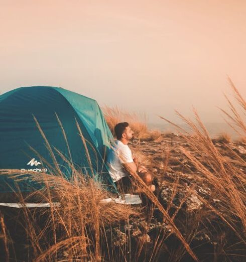 Solo Travel - Photo of a Man Sitting Outside the Tent