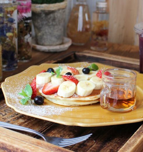 Breakfast - Pancakes garnished with fruits next to a Cup of juice