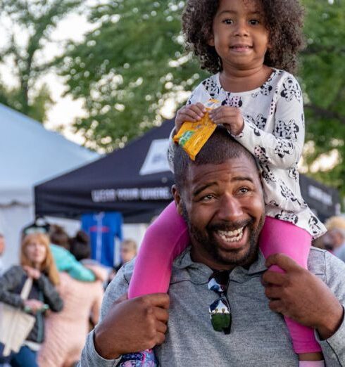 Families - Girl Sitting on Smiling Man's Shoulder