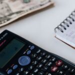 Budget - Crop unrecognizable accountant counting savings using notebook and calculator