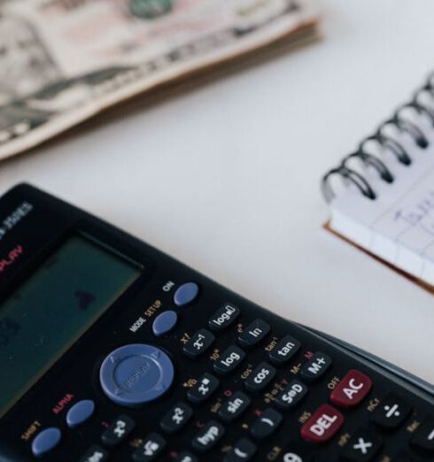 Budget - Crop unrecognizable accountant counting savings using notebook and calculator