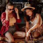 Souvenirs - Young Women Sitting on a Mat Having Fun Making Beads