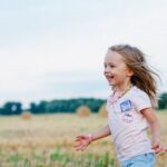 Kids - Smiling Girl Running Towards Left on Green Field