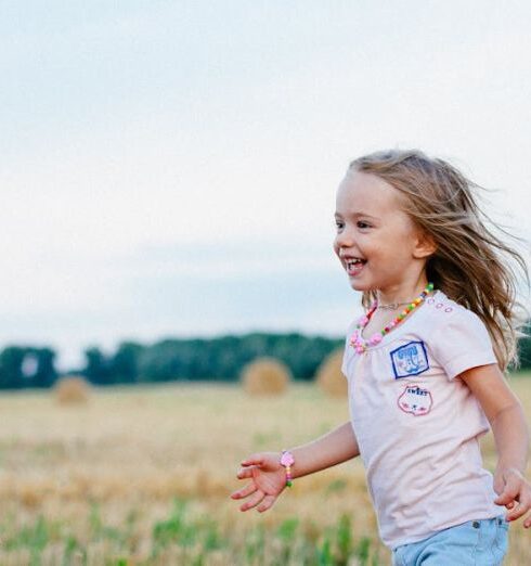 Kids - Smiling Girl Running Towards Left on Green Field